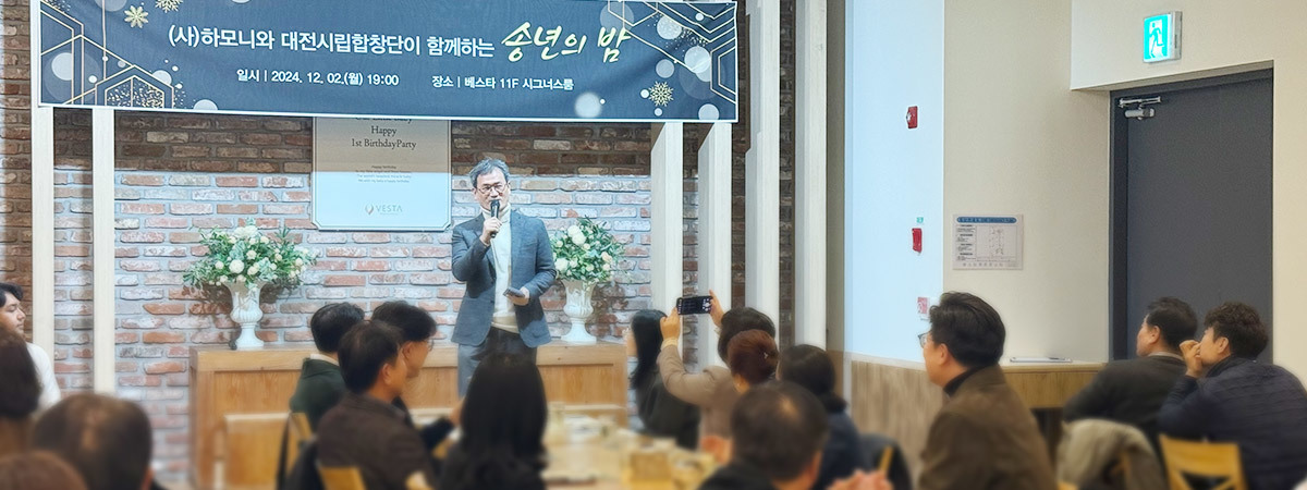 (사) 하모니 운영 관련 이미지로 (사)하모니와 대전시립합창단이 함께하는 송년의밤에 남성이 마이크를 들고 이야기하고있고 사람들이 경청하고있는 이미지